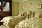 Guest bedroom with two beds and green wallpaper